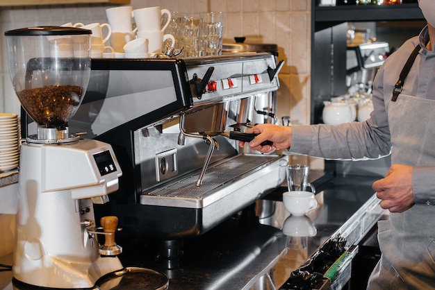 Closeup of a masked barista preparing a delicious coffee at the bar in a cafe