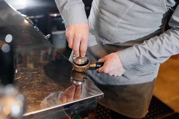 Closeup of a masked bartista preparing delicious delicious coffee at the bar in a coffee shop The work of restaurants and cafes during the pandemic