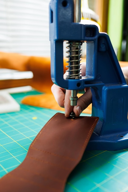 Closeup of the master's hands sewing handmade leather products A men's tanner connects the parts creating quality leather accessories Working process in a leather workshop