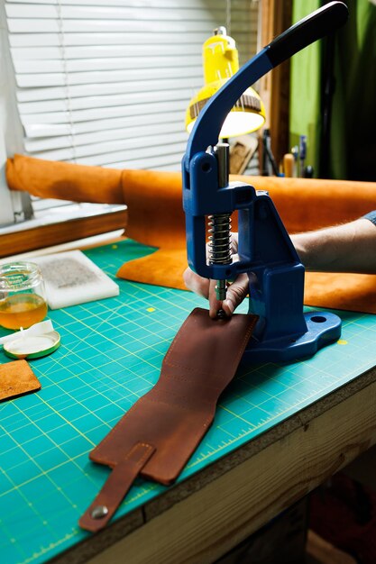 Closeup of the master's hands sewing handmade leather products A men's tanner connects the parts creating quality leather accessories Working process in a leather workshop