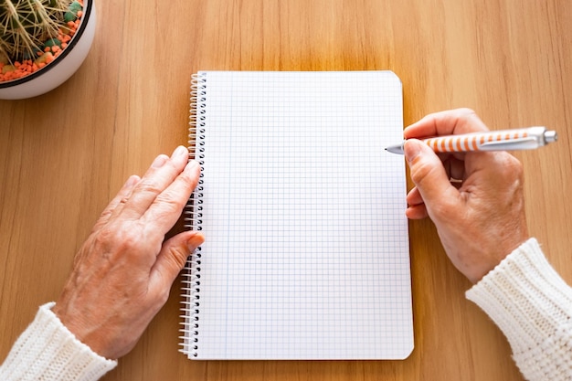 Closeup of mature woman hands with pen writing on notebook