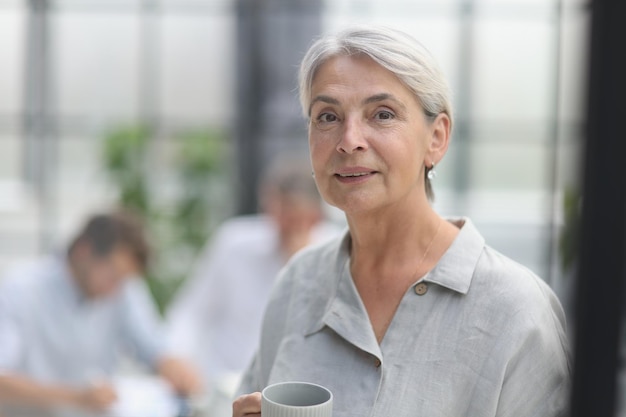 Closeup mature woman holding a cup in the office