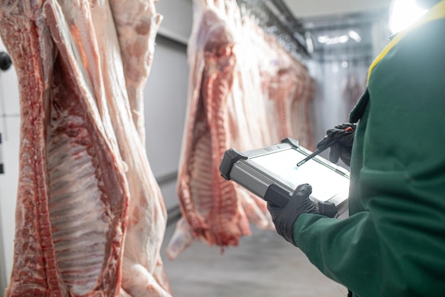 closeup of meat processing in the food industry the worker cuts raw pig storage in refrigerator