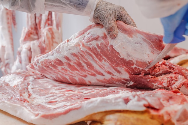 Closeup of meat processing in the food industry a worker cuts raw pork the concept of meat products