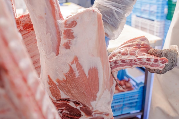 Closeup of meat processing in the food industry a worker cuts raw pork the concept of meat products