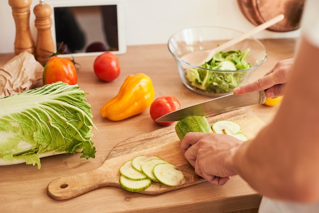 Closeup men's hands cut zucchini prepare a salad in the kitchen