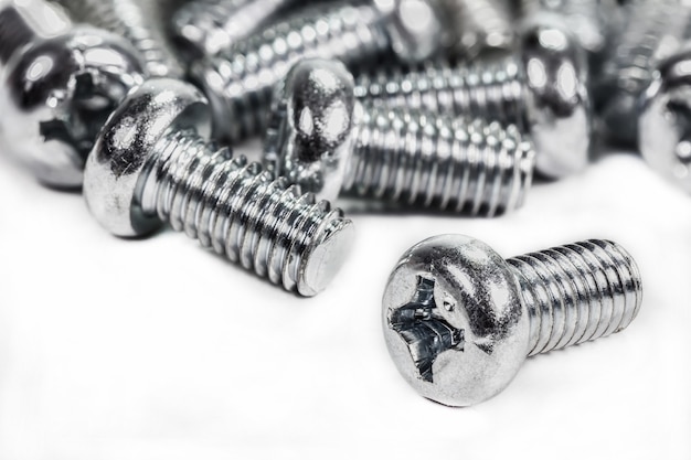 Closeup metal screw (bolt) and nuts on white background.