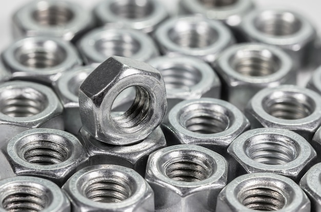 Closeup metal screw (bolt) and nuts on white background.