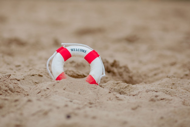 Closeup Of Miniature Lifebuoy Dig In The Sand At Beach.