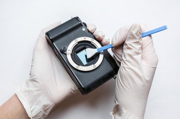 Photo closeup of mirrorless digital apsc dirty camera matrix sensor cleaning and maintenance with swab photographer cleaning photocamera on white background