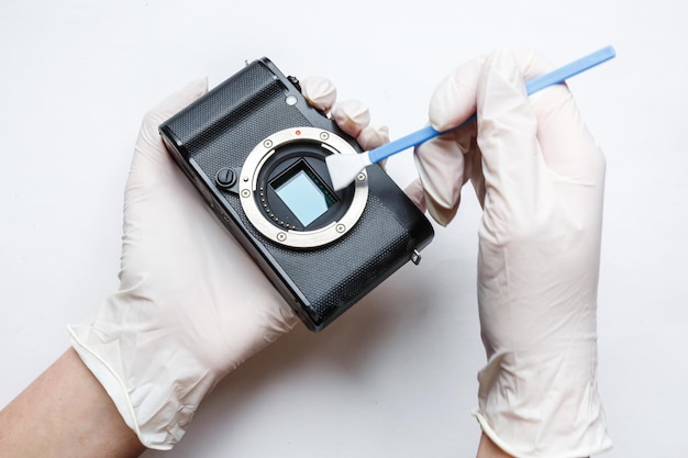 Photo closeup of mirrorless digital apsc dirty camera matrix sensor cleaning and maintenance with swab photographer cleaning photocamera on white background