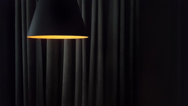 Closeup on a modern lamp against the background of the folds of curtains in dark colors with copy space