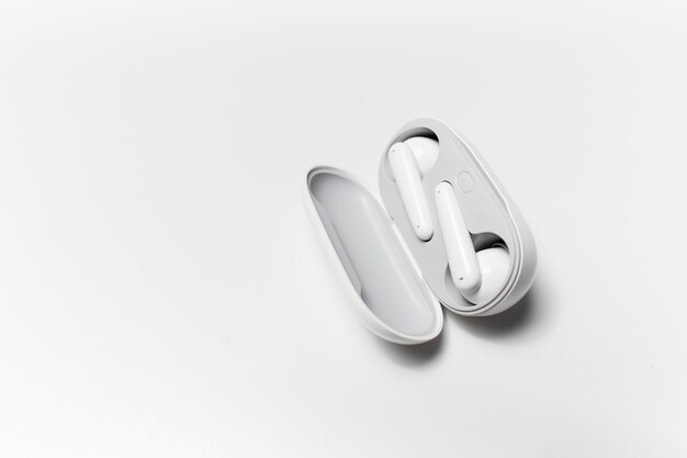 Closeup of modern wireless earbuds lying in charger case on white studio background