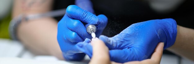 Closeup of nail specialist doing manicure to client using special apparatus hardware manicure