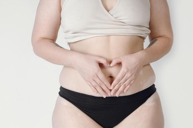 Closeup of a natural woman in underwear creating a heart shape on her hips.