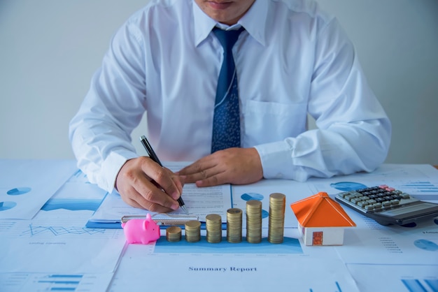 Closeup of new homeowner signing a contract of house sale or mortgage papers with a wooden toy house