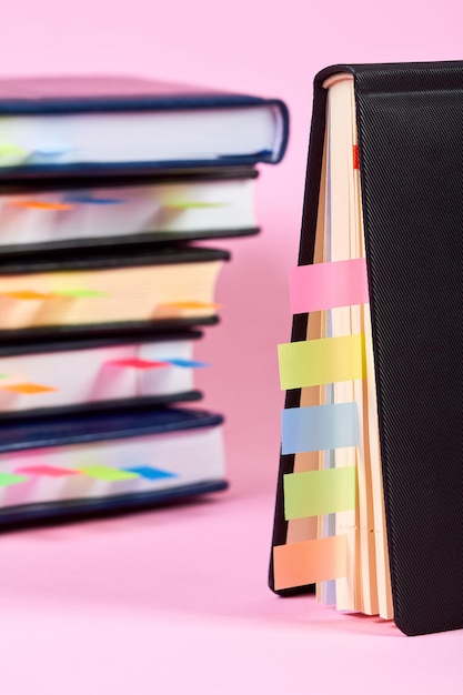 Closeup of a notepad with colorful sticky page markers on background of a stack of office notepads