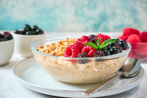 Closeup oatmeal with different berries and crushed nuts in a glass bowl healthy balanced food