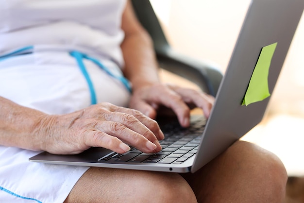 Closeup of old woman hands typing on modern laptop elderly female typing on laptop remote work