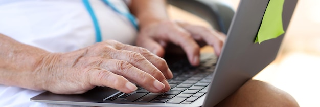 Closeup of old woman hands typing on modern laptop elderly female typing on laptop remote work