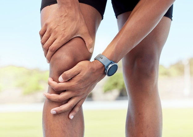 Closeup of one man holding sore knee from exercising outdoors Uncomfortable athlete suffering with painful leg injury fractured joint and inflamed muscles during workout Strain due to overexertion