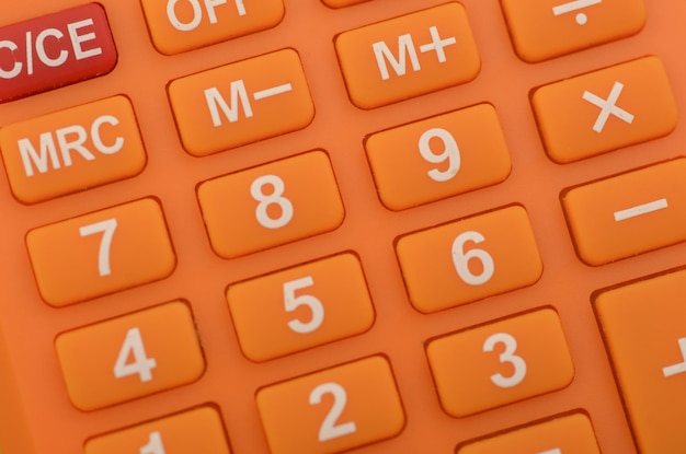 Photo a closeup of an orange calculator highlighting the numerical keys and basic arithmetic functions commonly used in everyday calculations