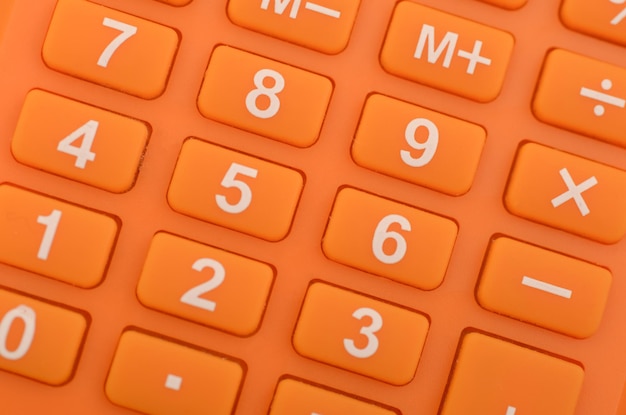 Photo a closeup of an orange calculator highlighting the numerical keys and basic arithmetic functions commonly used in everyday calculations