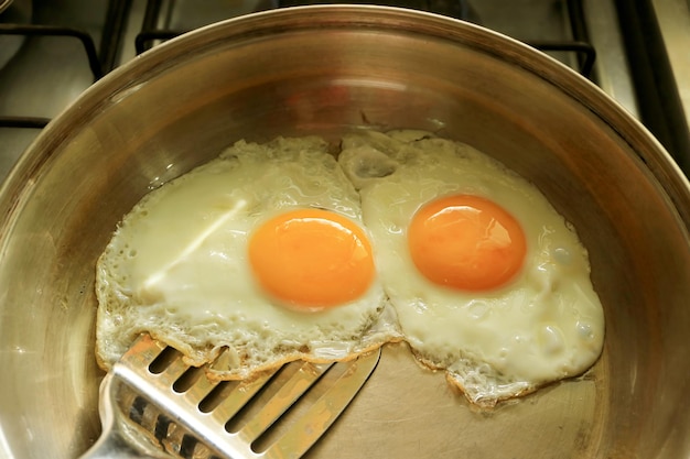 Closeup pair of eggs being fried in a pan