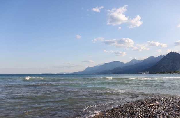 Closeup of pebble beach with cloudy blue sky on foggy mountains background mountain landscape