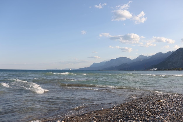 Closeup of pebble beach with wavy sea and white foam mountain landscape picturesque seashore