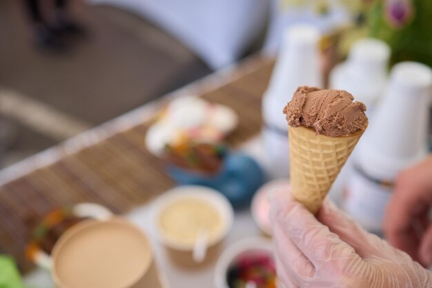 Photo closeup of person delighting in a chocolate ice cream cone at an outdoor market