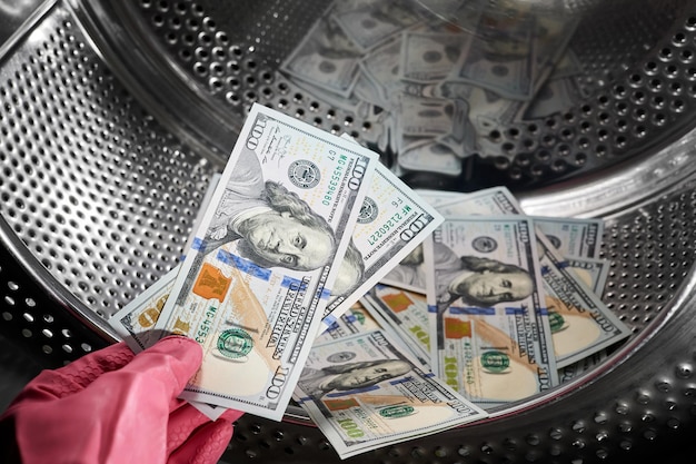 Closeup of a person hand in a rubber glove putting dollars in washing machine