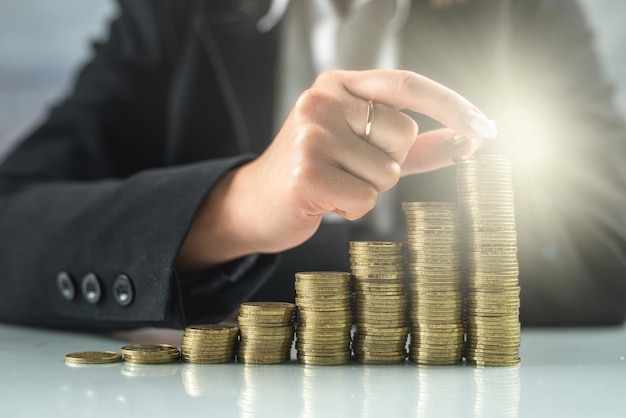 Closeup of a person holding hands on a glass table in front of stacked coins