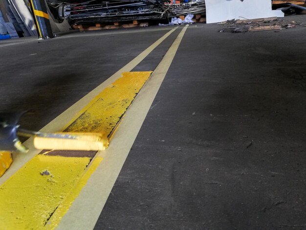 Closeup of a person painting a yellow line on a garage floor under the lights