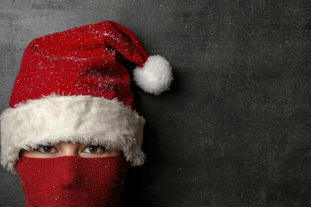 Photo closeup of person in red santa hat and mask