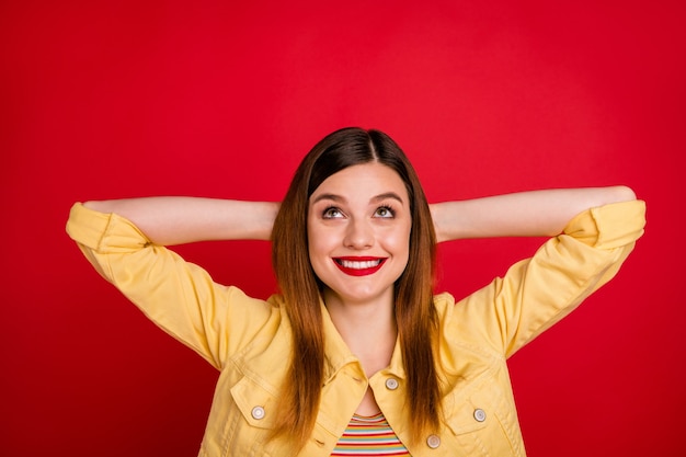 Closeup photo of attractive lady hold hands behind head toothy smile resting little nap free time look up empty space wear casual yellow blazer jacket isolated vibrant red color background