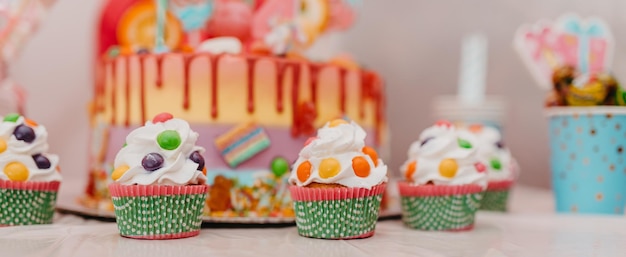 A closeup photo of a birthday cake and muffin on a decorated table