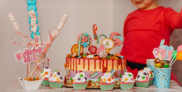 A closeup photo of a birthday cake and muffin on a decorated table