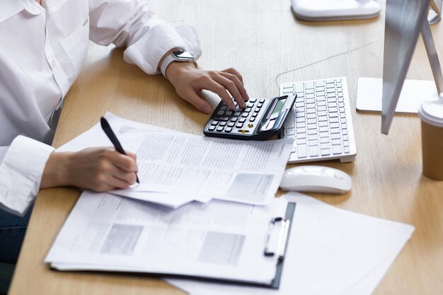 Closeup photo of a business womans hand on paper work an accountant calculates and summarizes the