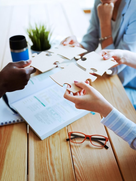 Closeup photo of businesspeople holding jigsaw puzzle