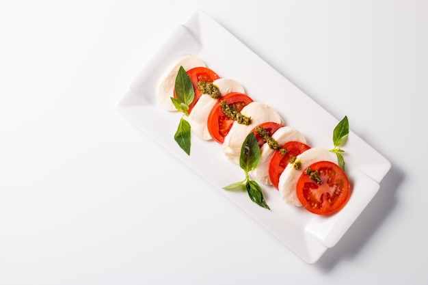 Closeup photo of caprese salad with ripe tomatoes basil buffalo mozzarella cheese Italian and Me