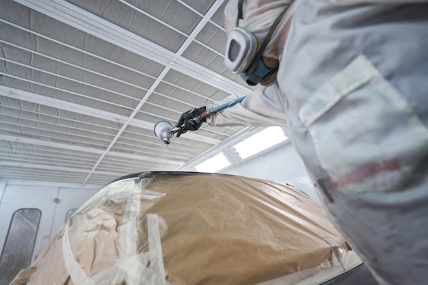 Closeup photo of car painter working with air gun