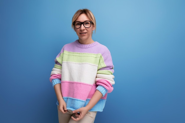 Closeup photo of a cute attractive blond woman in a striped sweater with glasses for vision on a