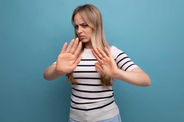 Closeup photo of a cute girl in casual clothes with a denial gesture on a blue isolated background