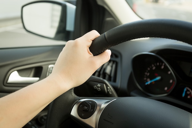 Closeup photo of female hand holding steering wheel with buttons