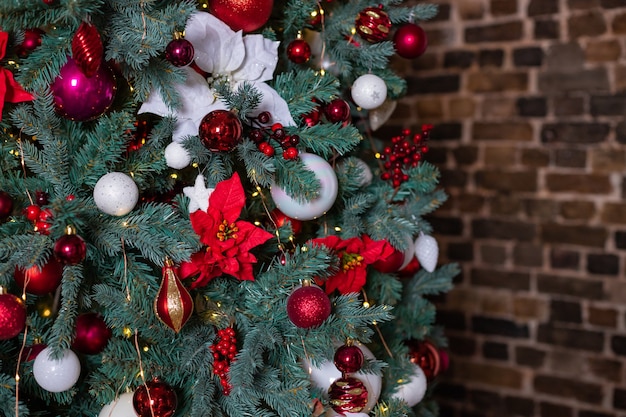 Closeup photo of festive balls on fir tree in living room white red christmas decorations hanging on...