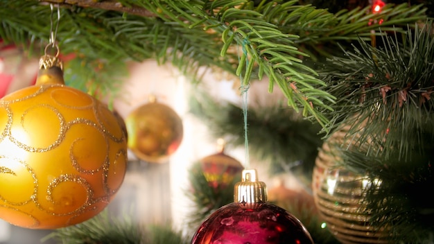 Closeup photo of golden baubles hanging on decorated Christmas tree