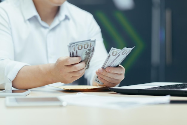 Closeup photo of the hands of a businessman man in a shirt counting money dollars cash a businessman