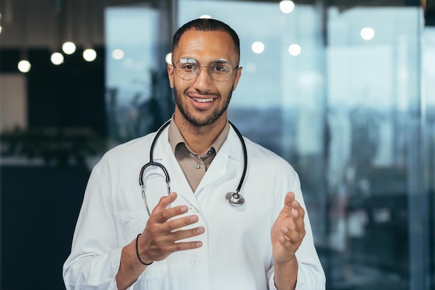 Closeup photo of hispanic doctor smiling and looking at web camera talking to colleagues and patient