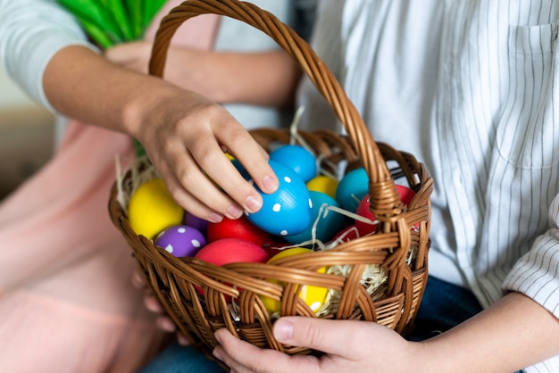 Closeup photo of little girl putting easter egg in nest.